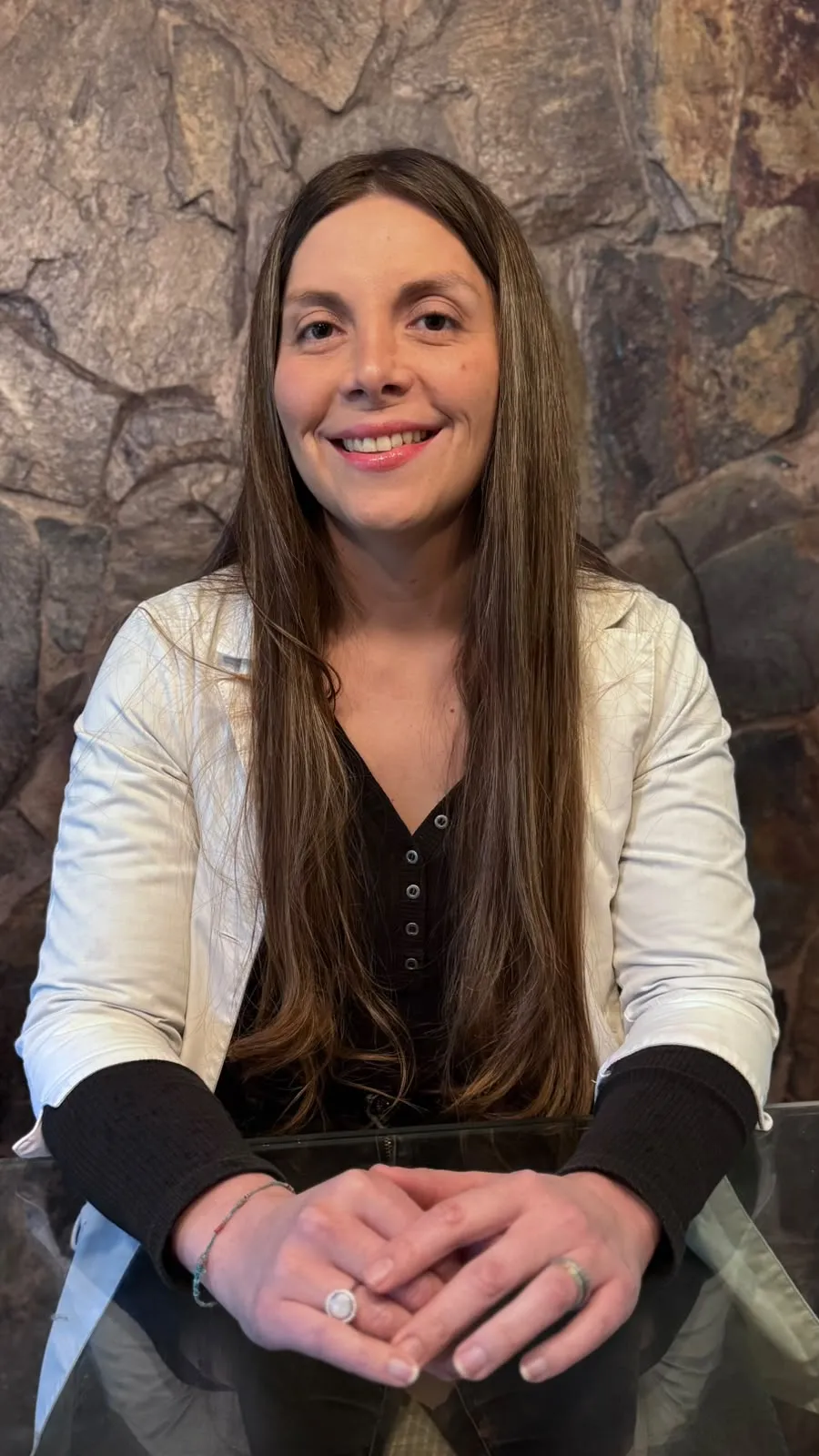 Dra. Pía Prenafeta sentada, sonriendo, con las manos juntas sobre la mesa